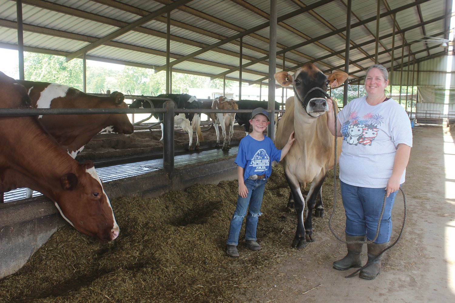 Michelle Eilenstine and her son Chase stand inside their freestall barn with “Bambi.”